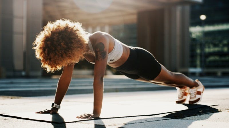Woman doing pushups on yoga mat exercise self-care