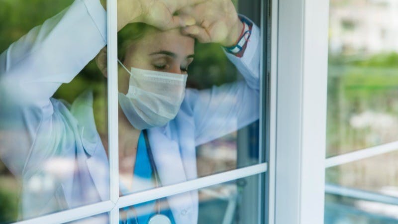 tired doctor leans against window resident