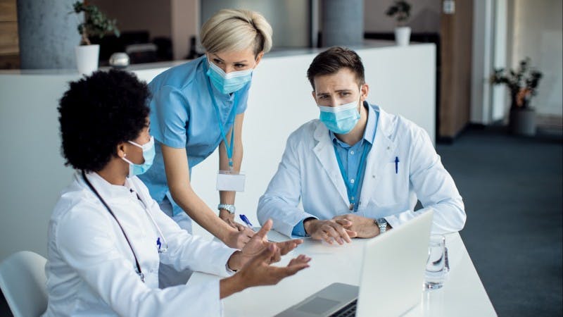 Three medical professionals gathered around a table