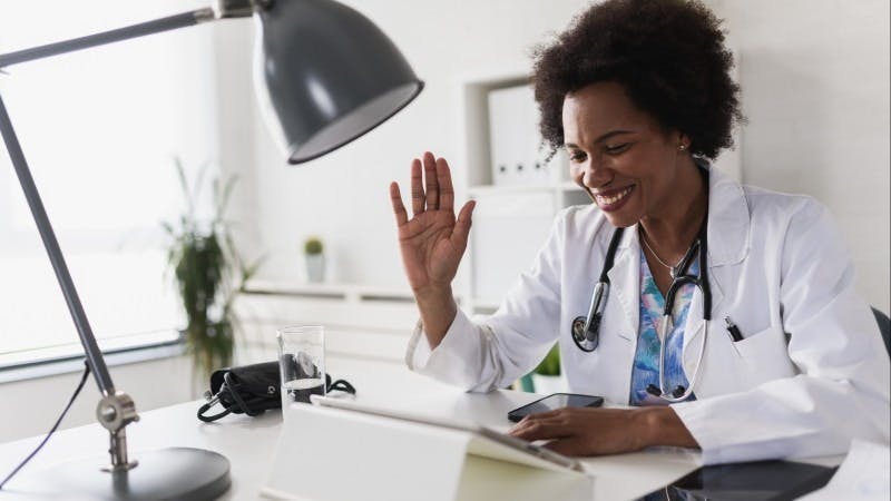 Female doctor waving at patient during telehealth visit